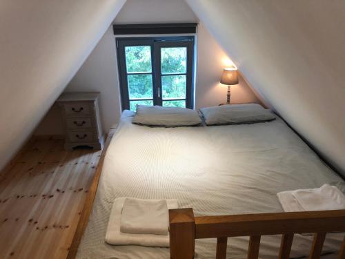 een slaapkamer op zolder met een bed en een raam bij Honeymoon, kleines aber feines Cottage am Strand in Kalkhorst