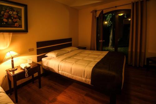 a bedroom with a bed and a lamp and a window at Hotel Meliana in Arequipa