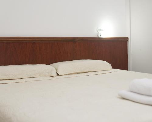 a white bed with a wooden headboard and two pillows at Hotel Garden in San Miguel de Tucumán