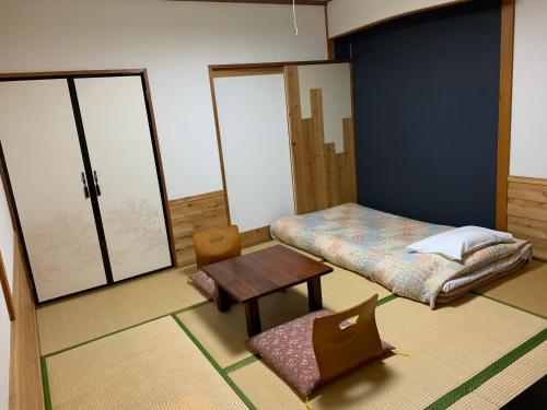 Turtle Inn Nikko في نيكو: غرفة بسرير وطاولة وكرسي