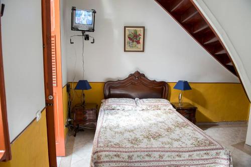 1 dormitorio con 1 cama y TV en la pared en Rio Antigo, en Río de Janeiro