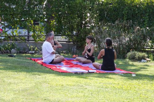 a group of people sitting on a blanket in the grass at El Valle Hostería in Mina Clavero