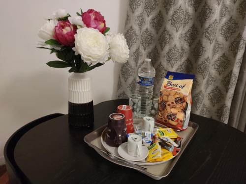 - une table avec un plateau de nourriture et un vase avec des fleurs dans l'établissement Appartement tout équipé au calme - RefKL, à Montfermeil