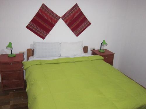 a bedroom with a green bed with two night stands at Kurumi Hostel in Cusco