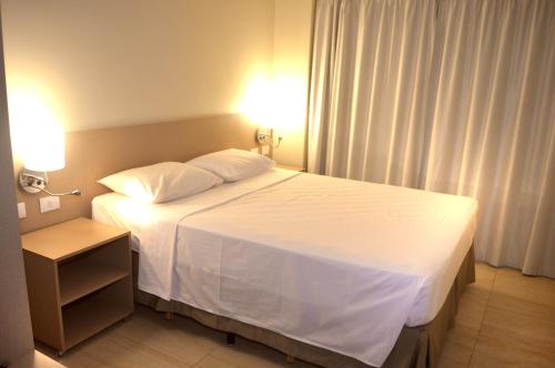 a bedroom with a white bed with two pillows at Salinas Park Resort in Salinópolis