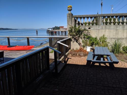 a picnic table and a bench on a balcony overlooking the water at Nimpkish Hotel in Alert Bay
