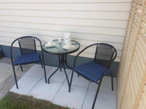 two chairs and a table with two cups and a candle at Thistle B&B in Napier