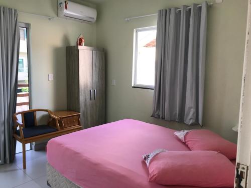 1 dormitorio con 1 cama rosa y 1 silla en Casa temporada Mariscal, Bombinhas-SC, en Bombinhas