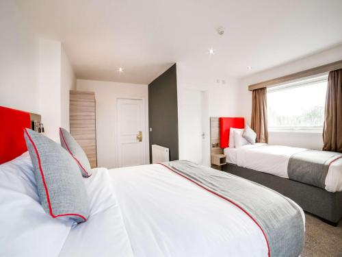 a hotel room with two beds and a window at The Connaught Hotel Wolverhampton in Wolverhampton
