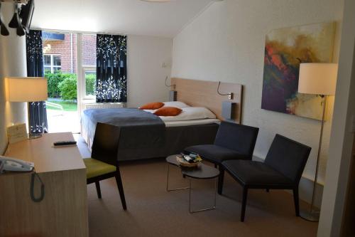 a bedroom with a bed and two chairs and a desk at Best Western Hotel Hillerød in Hillerød