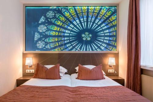 a bedroom with a bed with a large painting on the wall at Best Western Plus Monopole Métropole in Strasbourg