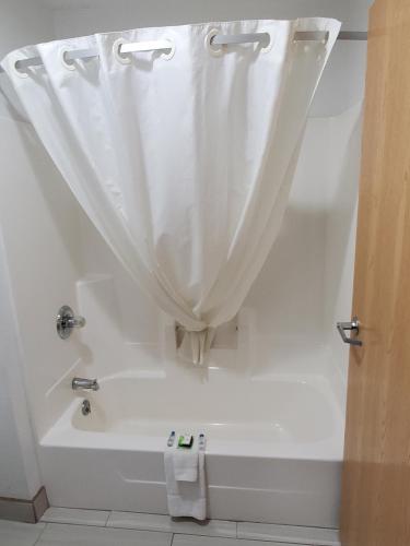 a white bath tub with a shower curtain in a bathroom at Super 7 Inn Tecumseh in Tecumseh