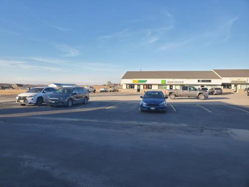 a parking lot with cars parked in front of a store at Super 7 Inn Tecumseh in Tecumseh