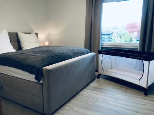 um quarto com uma cama e uma cadeira ao lado de uma janela em Wohnung an der Skiwiese - Boxspring - Balkon - 2 Smart TV - Carport em Braunlage
