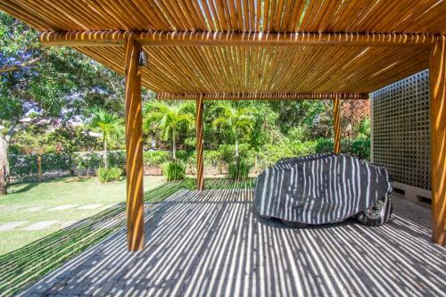 a wooden pergola with a chair sitting on a patio at Casa Itacimirim in Camaçari