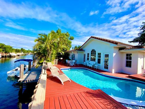 uma casa com uma piscina ao lado de uma massa de água em Villa-Coral-Ridge em Fort Lauderdale