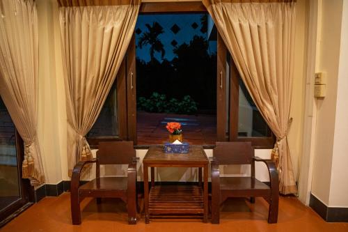 a dining room with a table and chairs and a window at JJ hut hotel in Chiang Rai