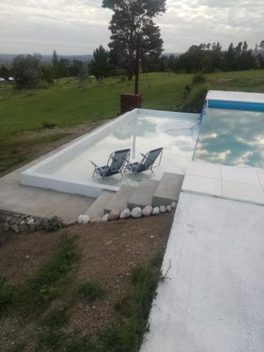 2 sillas sentadas junto a una piscina en Portalmorada, en Villa Yacanto