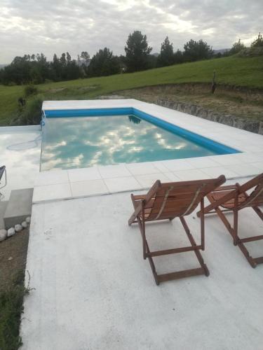 una piscina con 2 sillas y un banco en Portalmorada, en Villa Yacanto