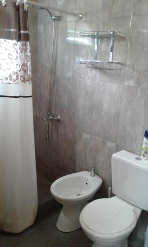 a bathroom with a white toilet and a shower at La Pergola, Sauce Monte Hermoso in Monte Hermoso