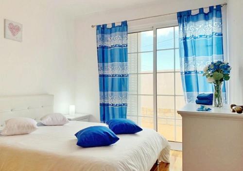 a bedroom with a bed with blue pillows and a window at Madeira Island Villa Oceane Ribeira Brava in Ribeira Brava