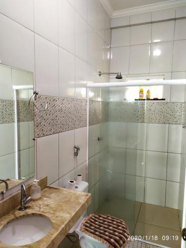 a bathroom with a sink and a glass shower at Pousada Barreirinhas House in Barreirinhas