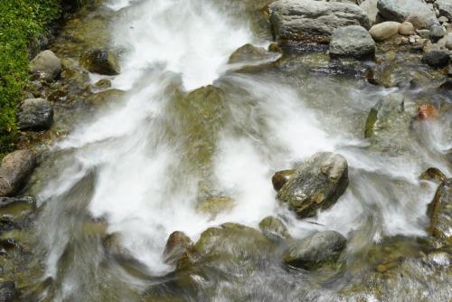 a stream of water with rocks in a river at Finca TRADICIONAL EL OTOÑO in Pijao
