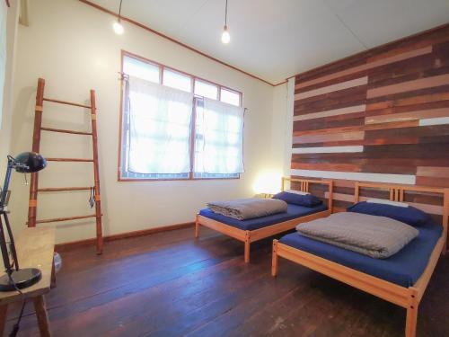 a bedroom with two beds and a wooden wall at Pickbaan in Lamphun