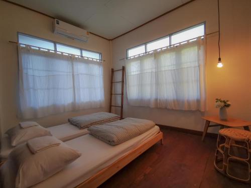 two beds in a room with two windows at Pickbaan in Lamphun