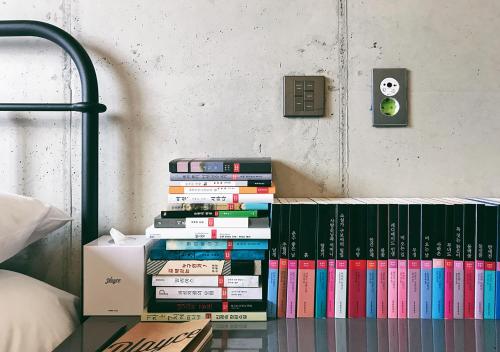a stack of books on a shelf in a bedroom at Playce Camp Jeju in Seogwipo