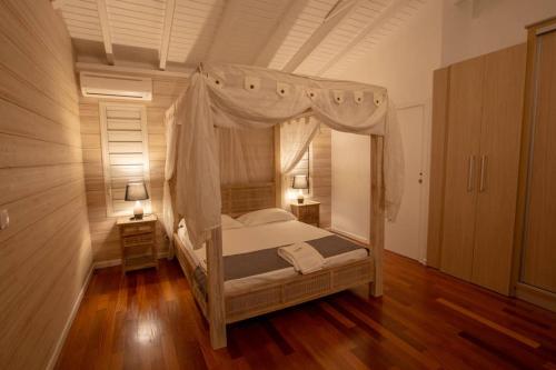 a bedroom with a canopy bed and wooden floors at Sunset Lodge in Bouillante