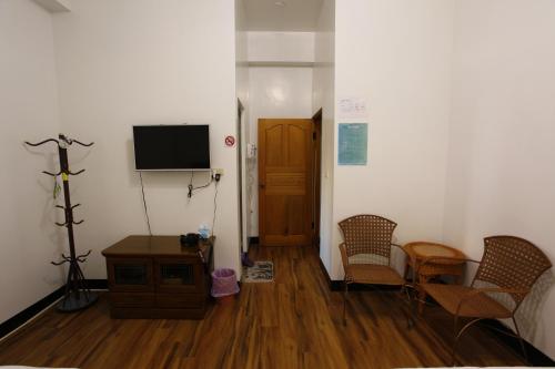 a room with a tv and chairs and a table at Cuiti B&B in Fenqihu