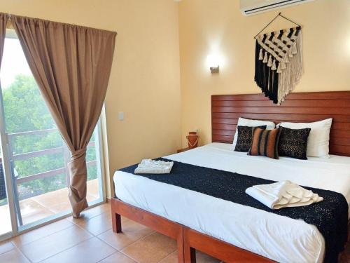 a bedroom with a bed and a large window at Tulum Nah in Tulum