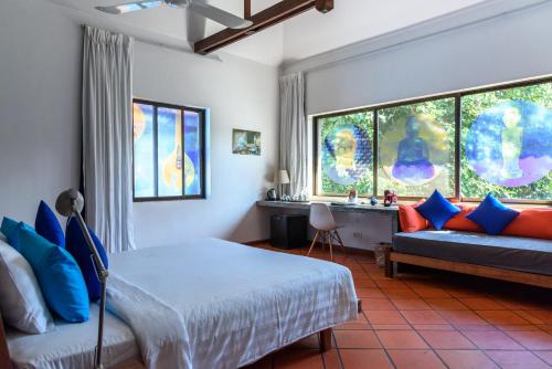 a bedroom with a bed and a couch and windows at Sala Baï Hotel & Restaurant School in Siem Reap