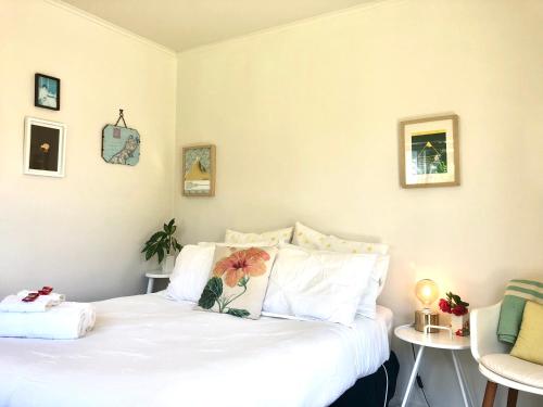 a bedroom with a white bed with a flower pillow at Sunny, Serene Studio @ Motueka in Motueka