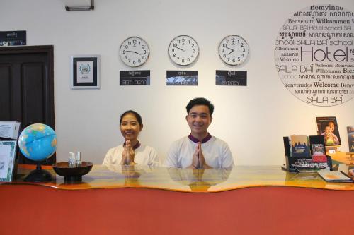 two men sitting at a table with clocks on the wall at Sala Baï Hotel & Restaurant School in Siem Reap