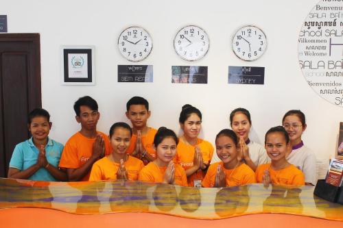 a group of people posing for a picture in a room with clocks at Sala Baï Hotel & Restaurant School in Siem Reap