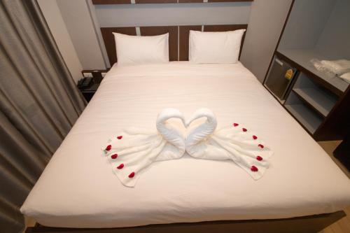 Dos cisnes haciendo forma de corazón en una cama en The Y Smart Hotel en Chiang Mai