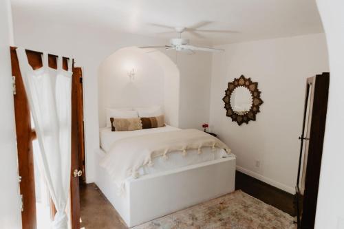 a white bedroom with a bed and a ceiling fan at Korakia Pensione in Palm Springs