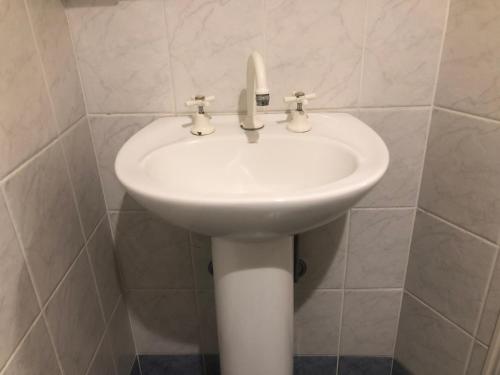 a white sink in a white tiled bathroom at Woodford Gardens in Woodford