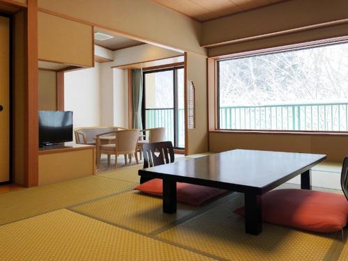 a living room with a table and a television at Hotel Yunojin in Minakami