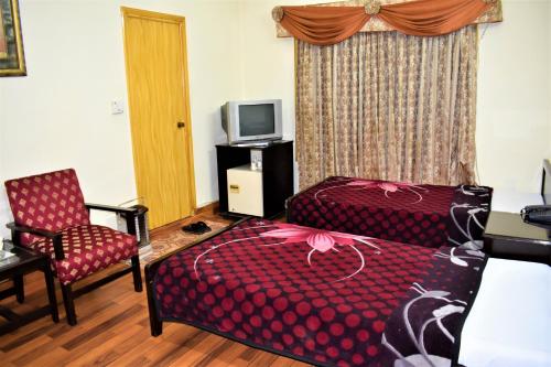 a bedroom with a bed and a chair and a tv at The City Lodge in Islamabad