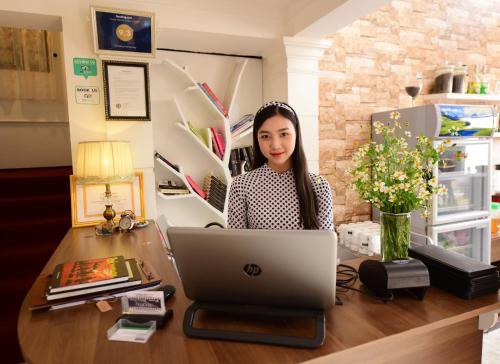 a woman sitting at a desk with a laptop computer at Timothy Homestay Hue in Hue