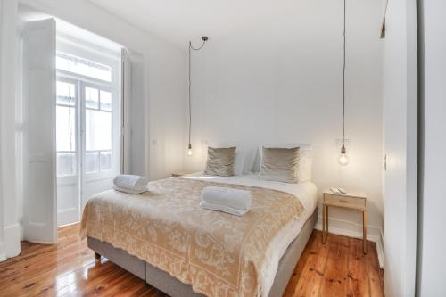 een witte slaapkamer met een groot bed en een raam bij Saldanha Pool & Garden in Lissabon