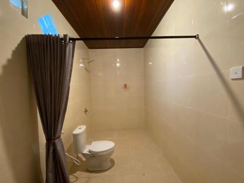 a bathroom with a toilet and a shower curtain at The Gradina Canggu in Canggu