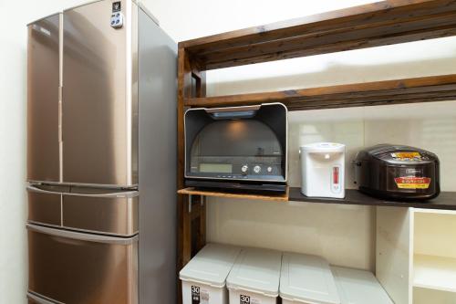 a kitchen with a refrigerator and a tv on a shelf at Regina Ishigaki Ocean Yonehara / Two-Bedroom Villa in Fukai