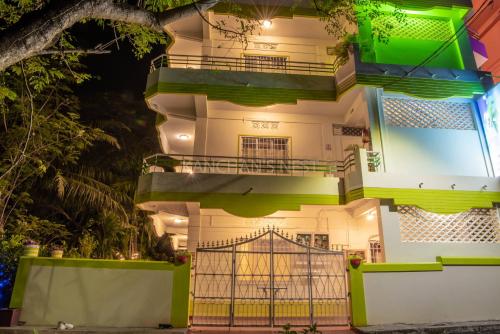a tall white building with green balconies and a gate at Kanchans Nest I Rooms & Suites near Port Blair Airport in Port Blair
