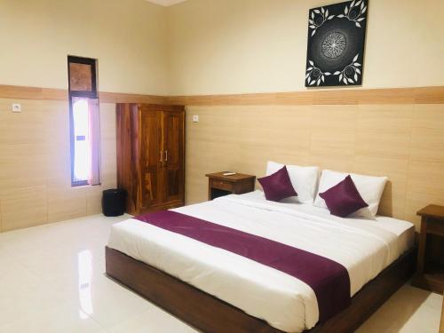 a bedroom with a large bed with purple pillows at The Gradina Canggu in Canggu