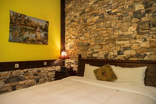 a bedroom with a stone wall and a bed at Provence Rose Lodge in Renai