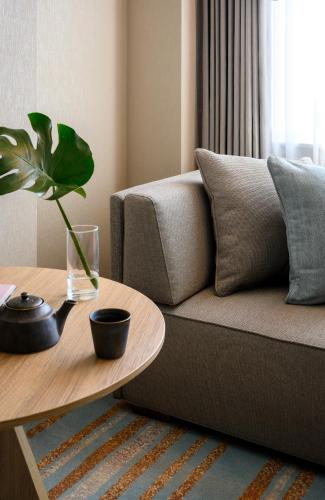 a living room with a couch and a table with a plant at Novotel Melbourne Central in Melbourne